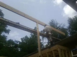 Carpenter setting a ridge beam over a new addition frame — Ice Dam Removal by Roofing Brothers in Barton
