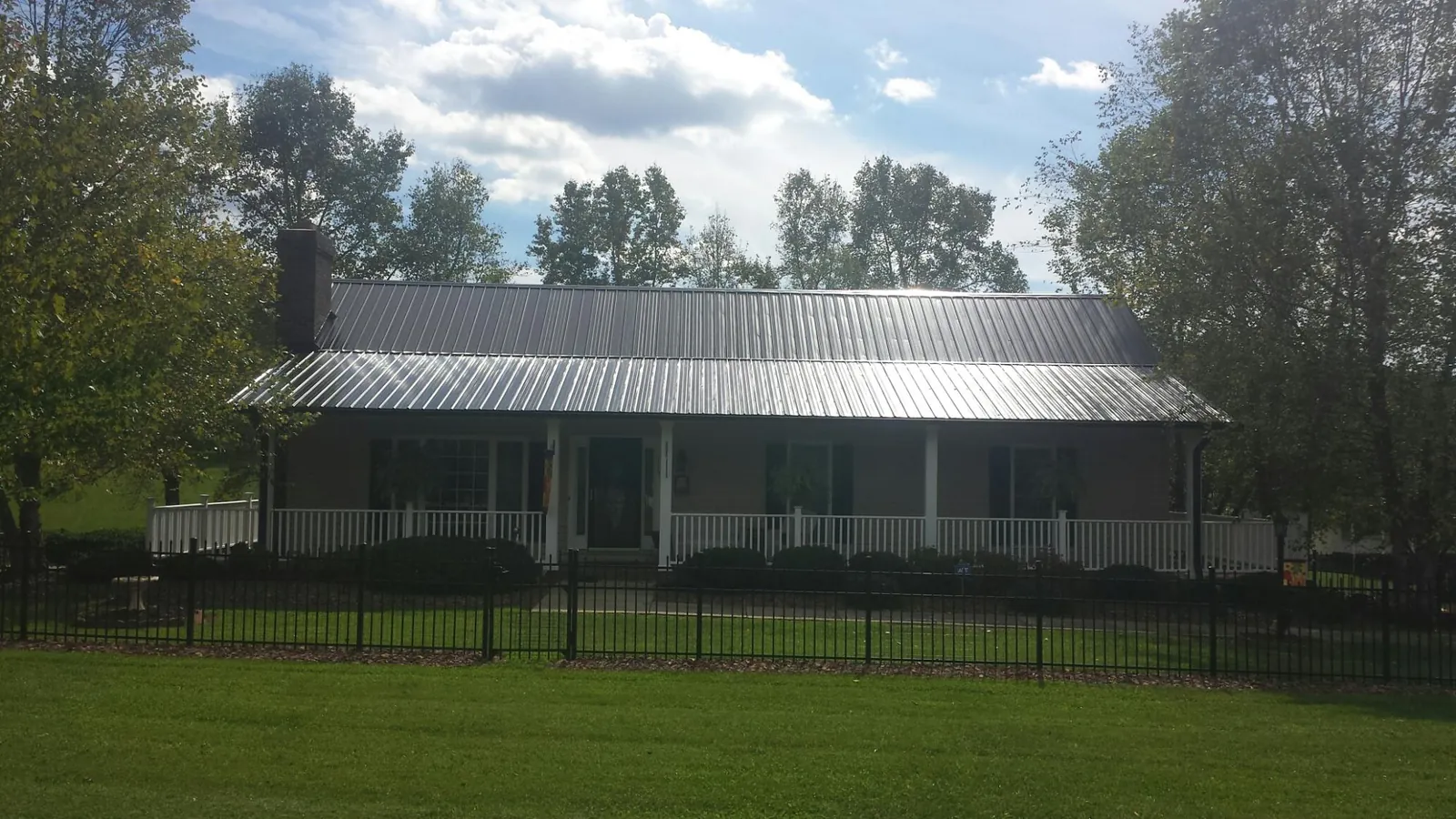 Gray metal roof on a brick ranch with a full width front porch — Gutter Guard Installation work by our crew in Barton
