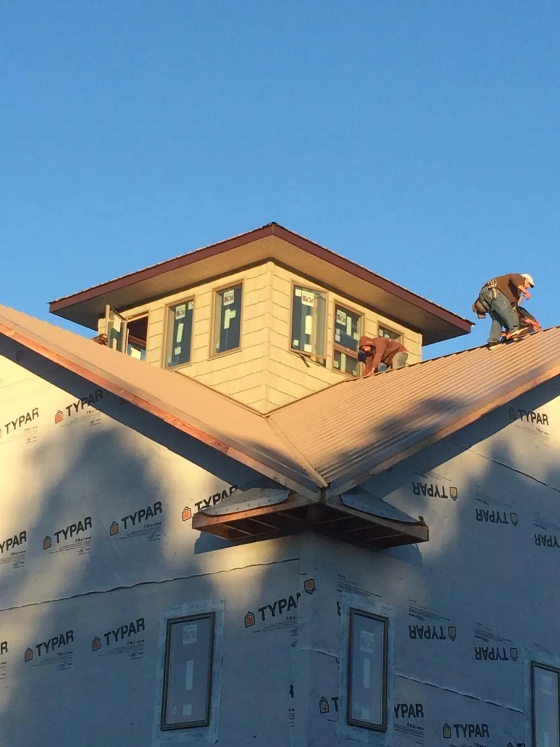 Roofers working around a rooftop cupola on a new metal roof at sunset — Roof Waterproofing in Barton by Roofing Brothers